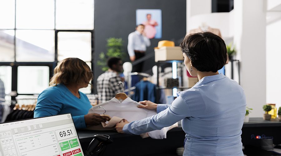 African american woman standing at counter desk discussing shirt material before buying it in clothing store. Stylish client shopping for formal wear, purchasing new fashion collection in boutique