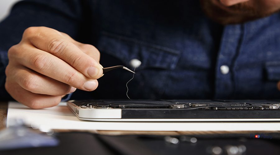 Close focus on angled esd tweezers with long hair removed from broken cooler of electronic device in service center