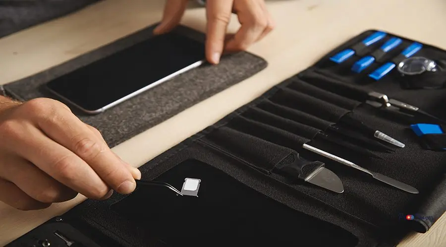 Computer and phone repairment service Close up on hand with pincher tool holding sim-card slot with nano sim above black magnet plate on portable tookit for electronic repeirment service