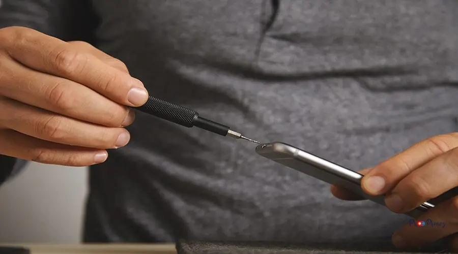 Computer and phone repairment service Close view on micro driver with small screw on it, dissasembling broken phone process