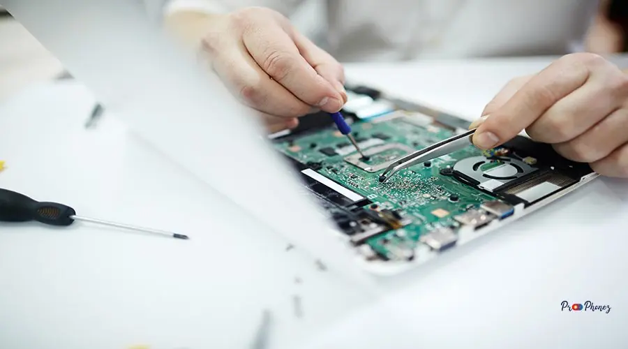 Closeup of Fixing Disassembled Laptop Closeup shot of male hands repairing parts in disassembled laptop using screwdriver and different tools on table in workshop