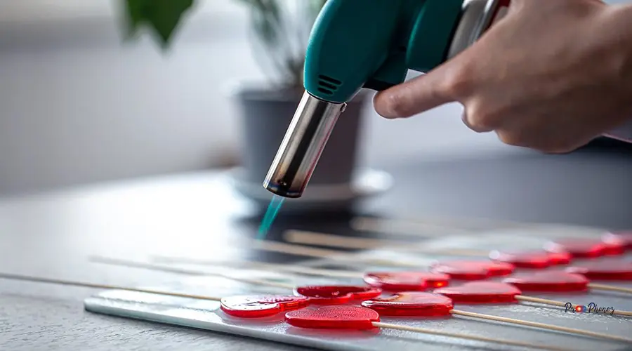 Close-up, the process of making heart-shaped lollipops. Cooking heart-shaped lollipops, roasting marmalade with a gas burner, a workshop of healthy handmade sweets.