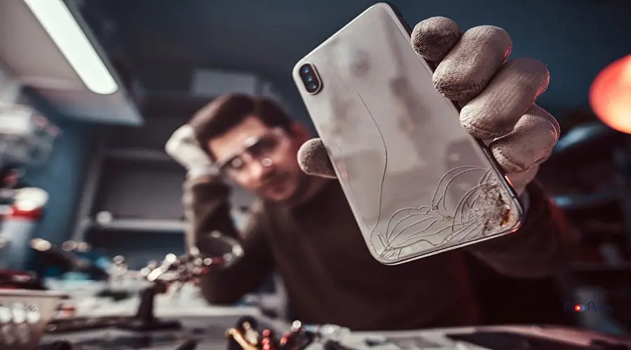 Electronic technician repair damaged smartphone in the workshop Electronic technician showing a modern smartphone with a broken body in a repair shop