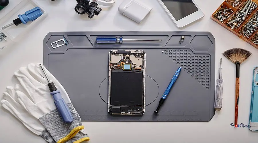 Elements of Faulty Mobile Phone Before Repairing in Workshop Flat lay shot of parts of disassembled cell phone and work tools displayed on table before repairing