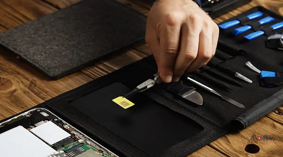 Electronic repair service Hand holds tweezers with gsm sim card above tool bag in fixing service lab