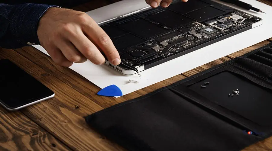 Electronic repair service Close focus on hand that uses angled esd tweezers to remove dust from electronic boards of broken slim computer laptop to fix it and make to work again.