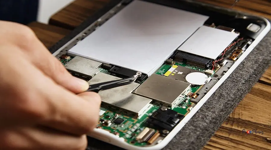 Electronic repair service Hand uses tweezer to pick up small crew that holds the battery on motherboard Repairing broken electronic service