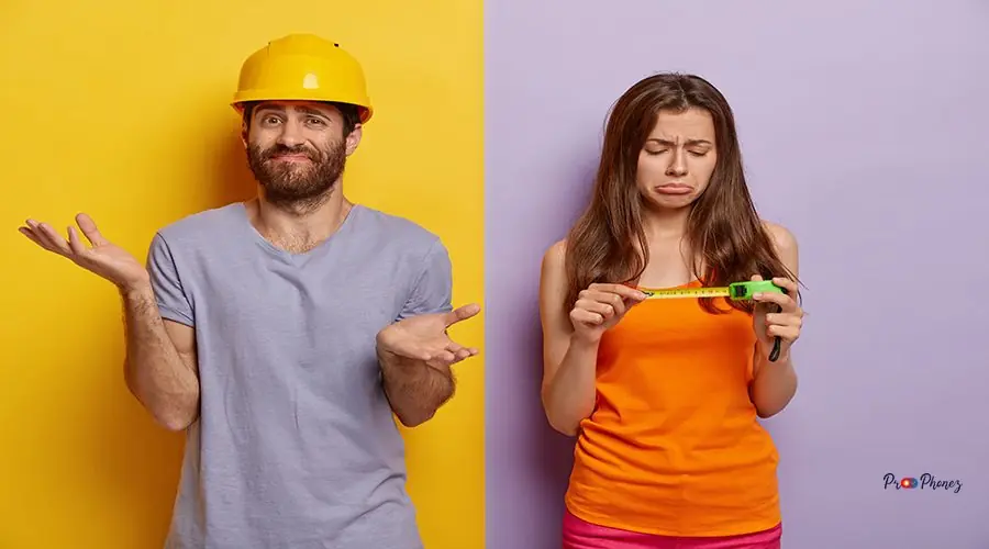 Home improvement concept. Dissatisfied sorrowful woman looks at measuring tape, helps husband with house renovation, hesitant man stands confused, spreads palms, wears yellow hardhat, purple t shirt Home improvement concept. Dissatisfied sorrowful woman looks at measuring tape, helps husband with house renovation, hesitant man stands confused, spreads palms, wears yellow hardhat, purple t shirt