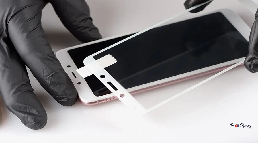 Human hands are removing a protective film from the screen of a A man is installing a protective glass on the screen of a smartphone.
