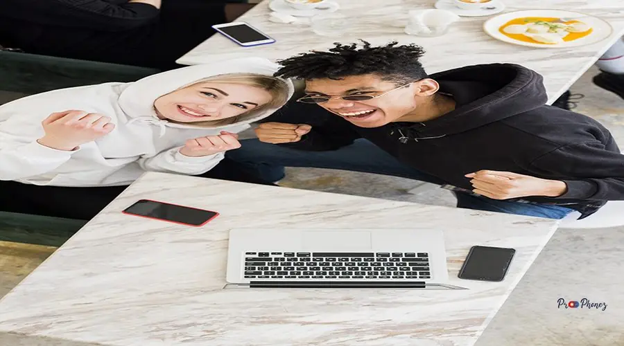 interracial-young-couple-clenching-their-fists-looking-up-with-mobile-phone-laptop-table interracial-young-couple-clenching-their-fists-looking-up-with-mobile-phone-laptop-table