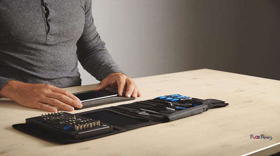 Man prepares to disassemble phone at home with his personal portable tool kit on table Space for your text on right side