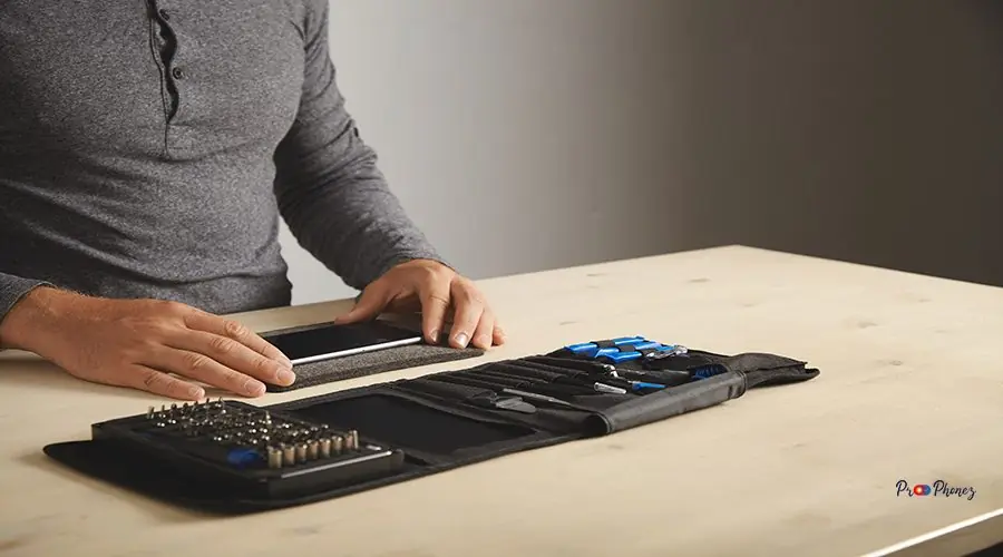 Computer and phone repairment service Man prepares to disassemble phone at home with his personal portable tool kit on table Space for your text on right side