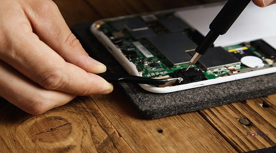 Master uses special tools to disassemble electronic device carefully Pincers and bit screw driver closeup