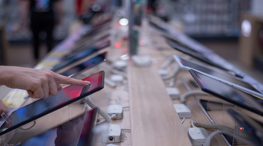 Faceless caucasian woman chooses a smartphone in an electronics store. Close-up of a female hand with a phone tester.