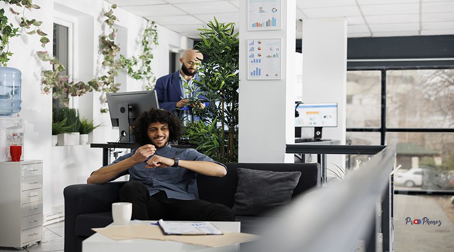 Happy businessman recording business ideas using smartwatch app while sitting on couch in office. Smiling arab executive manager talking on electronic wearable watch device