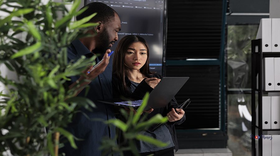 Multi ethnic team of system developers analyzing html code on laptop computer, checking artificial intelligence project. Programmers working on machine learning software, developing new interface.
