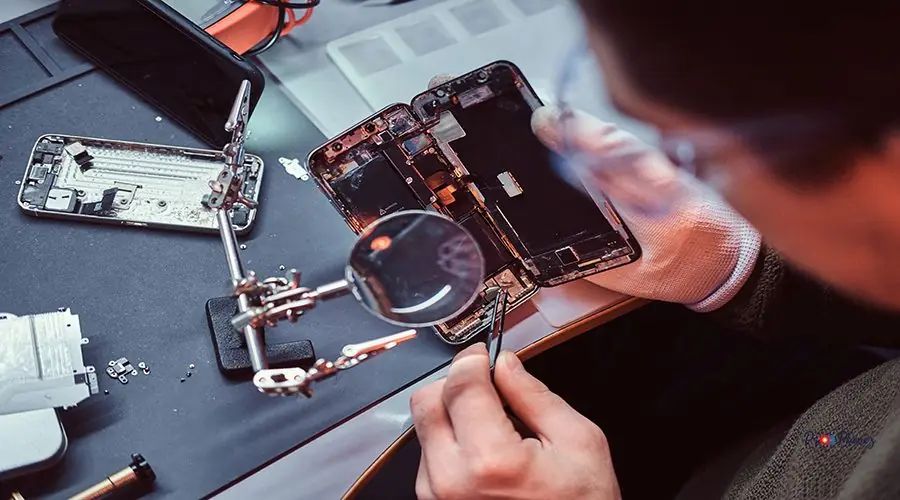 Technician carefully inspect the internal parts of the smartphone in a modern repair shop Repairman uses magnifier and tweezers to repair damaged smartphone. Close-up photo of a disassembled smartphone.