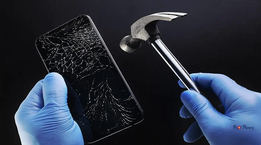 Rough repair the phone. A smartphone with a cracked display and a hammer in the hands of a master. Rough repair the phone. A smartphone with a cracked display and a hammer in the hands of a master. Background.
