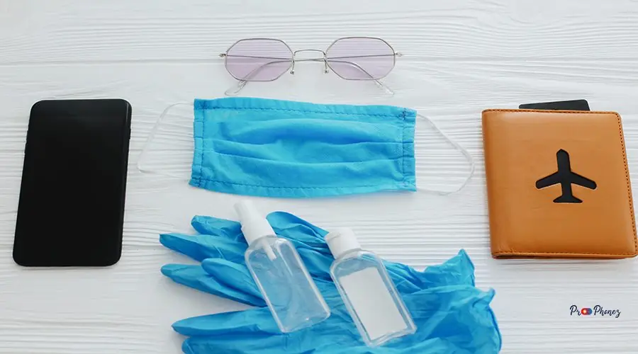 Safe travel in summer 2020. Blue face mask, gloves, antiseptic a Safe travel in summer 2020. Blue face mask, gloves, antiseptic and disinfectant, passport, sunglasses and phone on white background. Coronavirus vacation protection measures