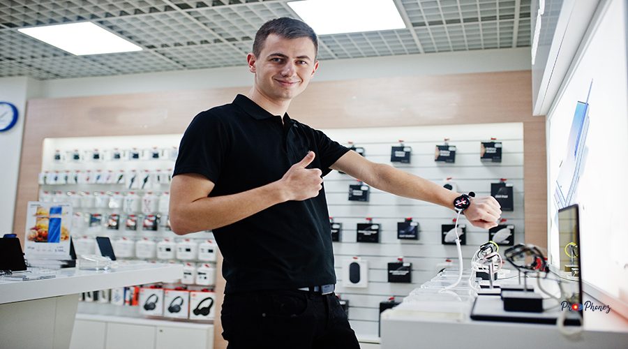 Seller man mobile phone professional consultant in tech store or shop check new smart watches.