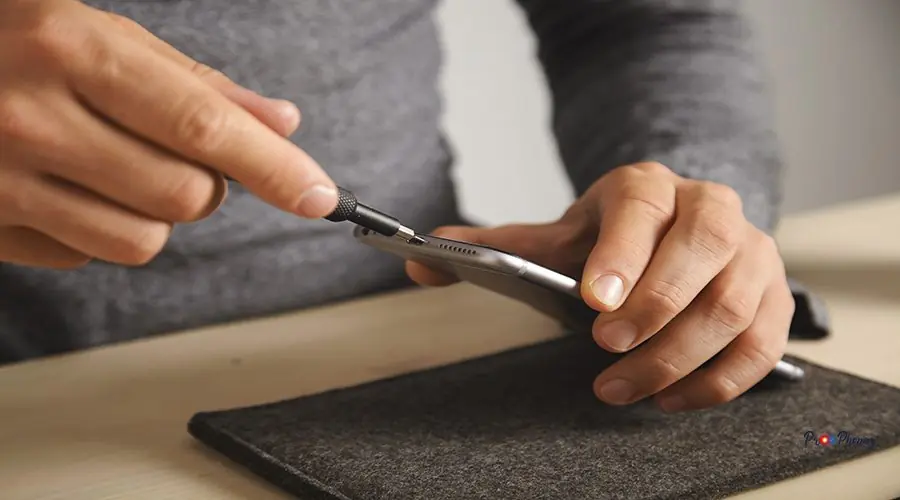 Computer and phone repairment service Techician uses driver to unscrew small screws on smartphone body