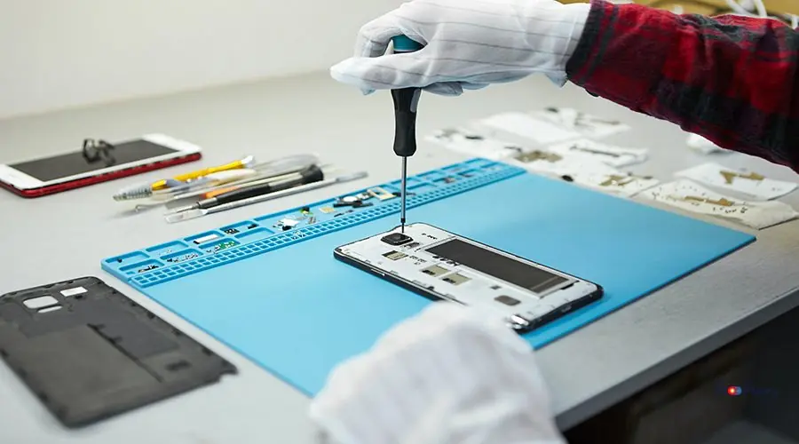 Cropped shot of male technician in antistatic gloves using screw Cropped shot of male technician in antistatic gloves using screwdriver to disassemble borken mobile phone, going to repair motherboard, sitting at his workplace in laboratory with needed equipment