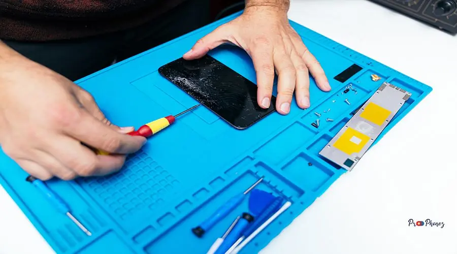 Repair Specialist Fixing a Smartphone with Precision Tools Technician carefully disassembling a broken smartphone on blue mat