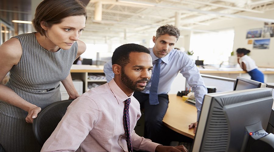 Three business colleagues working together around a monitor