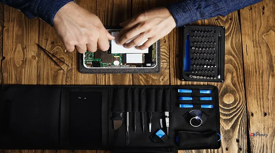 Electronic repair service Top view hands works on broken electronic gadget to fix it near tool bag and on wooden table in service shop