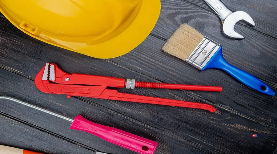 top view of pattern from set of construction tools as screwdriver pipe wrench safety helmet paint brush and open-end wrench on wooden background back glass replacement iphone