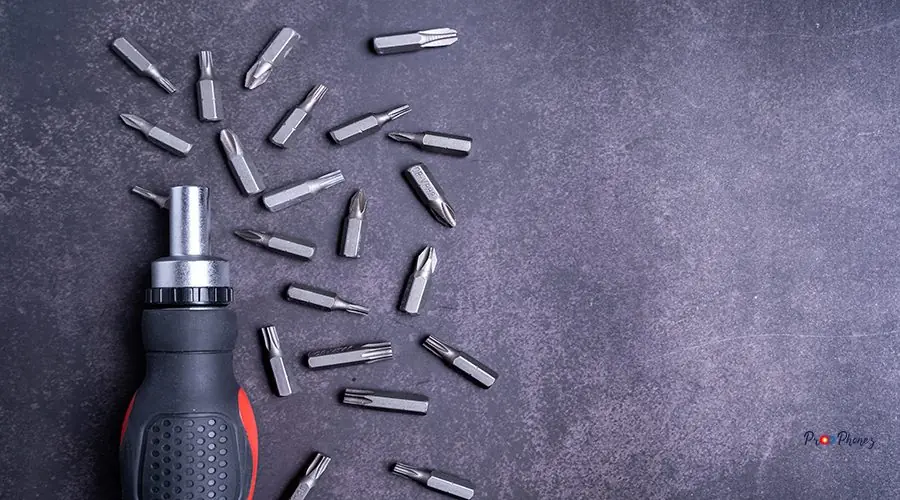Top view of a screwdriver with bits on gray background back glass replacement iphone