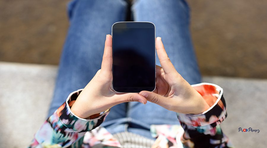 Young woman using a touchscreen smartphone wearing casual clothes