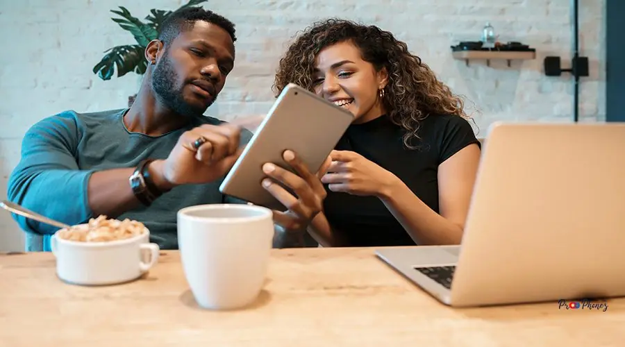 Couple using a digital tablet and a laptop while having breakfas iPhone Screen